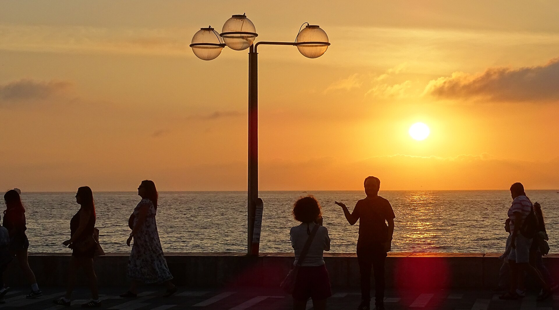 Personas caminando al atardecer por el Malecón de Mazatlán junto al Pacífico